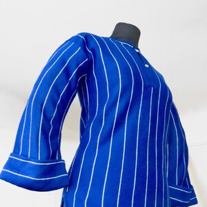 May include: A blue and white striped long-sleeved shirt with a rounded hem and button closure at the neck.