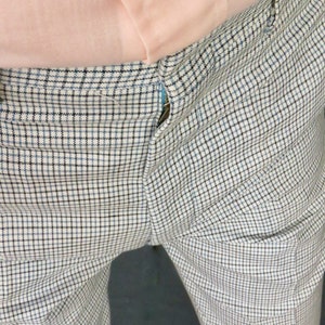 Op de afbeelding: Een witte broek met een zwart-blauw geruit patroon. De broek heeft een rits en een knoopsluiting.