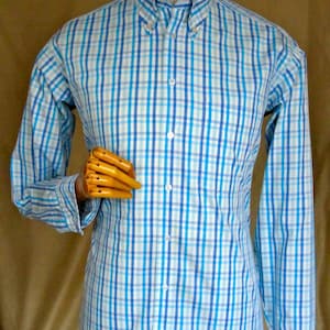 Puede incluir: Una camisa de manga larga con botones y un estampado de cuadros azules y blancos.