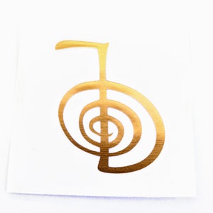 May include: A gold-colored metal sticker with a stylized symbol, known as the Reiki symbol, representing balance and harmony.