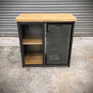 May include: A black metal cabinet with a wooden top and a glass door. The cabinet has two shelves and a built-in wine cooler. The cooler has a digital display and a glass door.