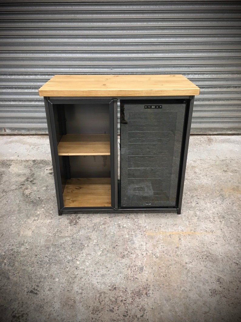 May include: A black metal cabinet with a wooden top and a glass door. The cabinet has two shelves and a built-in wine cooler. The cooler has a digital display and a glass door.