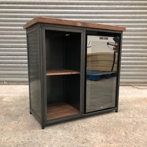 May include: A black metal bar cabinet with a wooden top and a built-in wine cooler. The cabinet has two shelves and a sliding door. The wine cooler has a glass door.