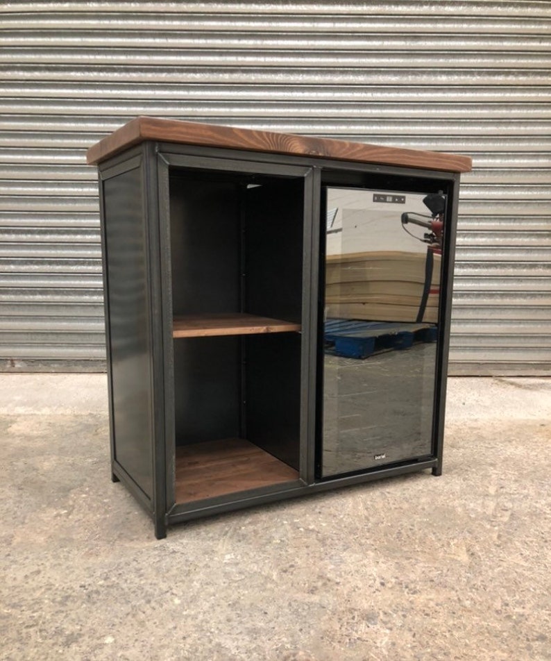May include: A black metal bar cabinet with a wooden top and a built-in wine cooler. The cabinet has two shelves and a sliding door. The wine cooler has a glass door.