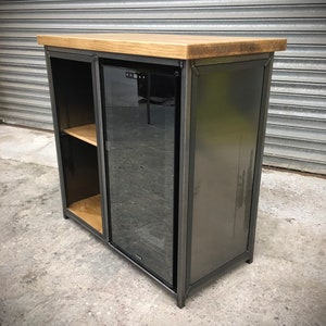 May include: A black metal cabinet with a wooden top and a glass door. The cabinet has a shelf inside and a built-in wine cooler.