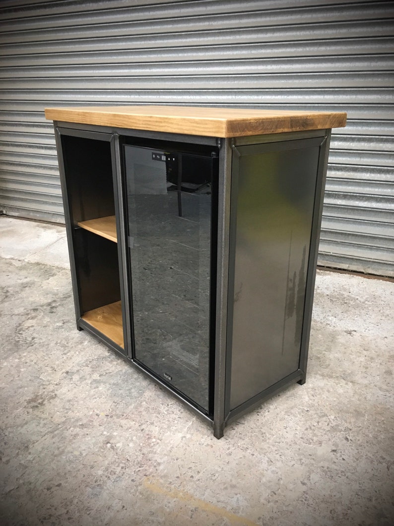 May include: A black metal cabinet with a wooden top and a glass door. The cabinet has a shelf inside and a built-in wine cooler.