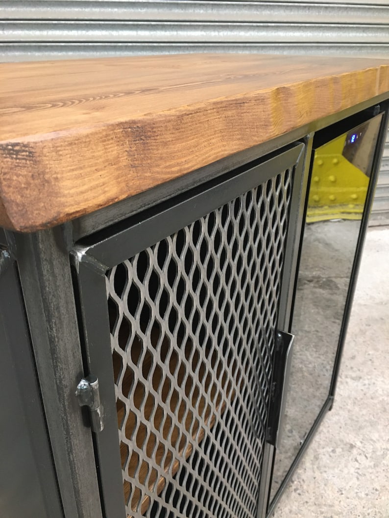 Op de afbeelding: Een zwarte metalen kast met een houten bovenblad en een deur van draadgaas. De kast heeft een ingebouwde wijnkoeler met een glazen deur.