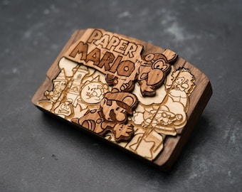 May include: A wooden Nintendo 64 game cartridge replica featuring the Paper Mario game cover art. The cartridge is made of wood and features a detailed carving of the game's characters, including Mario, Luigi, and Bowser. The cartridge is a great gift for any Nintendo fan.