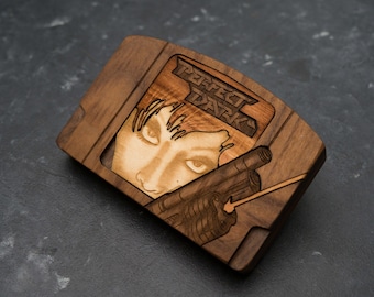 May include: A wooden Nintendo 64 game cartridge replica featuring the cover art for the game "Perfect Dark". The cartridge is made of dark wood and features a laser-engraved image of the game's protagonist, Joanna Dark, holding a gun.