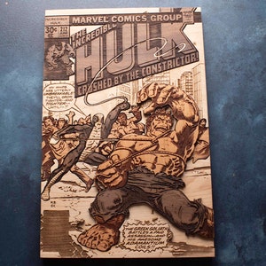 May include: A wood-carved replica of a vintage comic book cover featuring The Incredible Hulk. The cover is titled "The Incredible Hulk" and features the Hulk in a green and brown color scheme, being restrained by a rope. The text on the cover reads "Crashed by the Constrictor!" and "The Green Goliath battles a paid assassin--and his awesome adamantium coils!!"