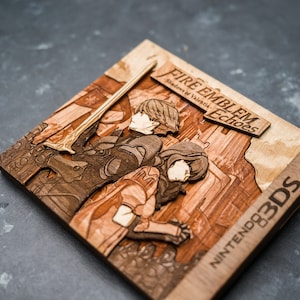 May include: A wooden 3DS game case with a 3D laser-cut design of the characters from Fire Emblem Echoes: Shadows of Valentia. The case is brown and features the game title and Nintendo 3DS logo.
