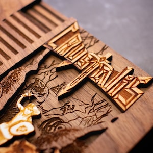 May include: A wooden box with a carved design of a video game character and the game's title "Castlevania". The box is made of dark wood and has a light brown finish.