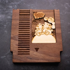 May include: A wooden NES game cartridge replica featuring the characters from the game "The Bubble Bobble". The cartridge is made of walnut wood and has a laser-engraved image of the game's characters.