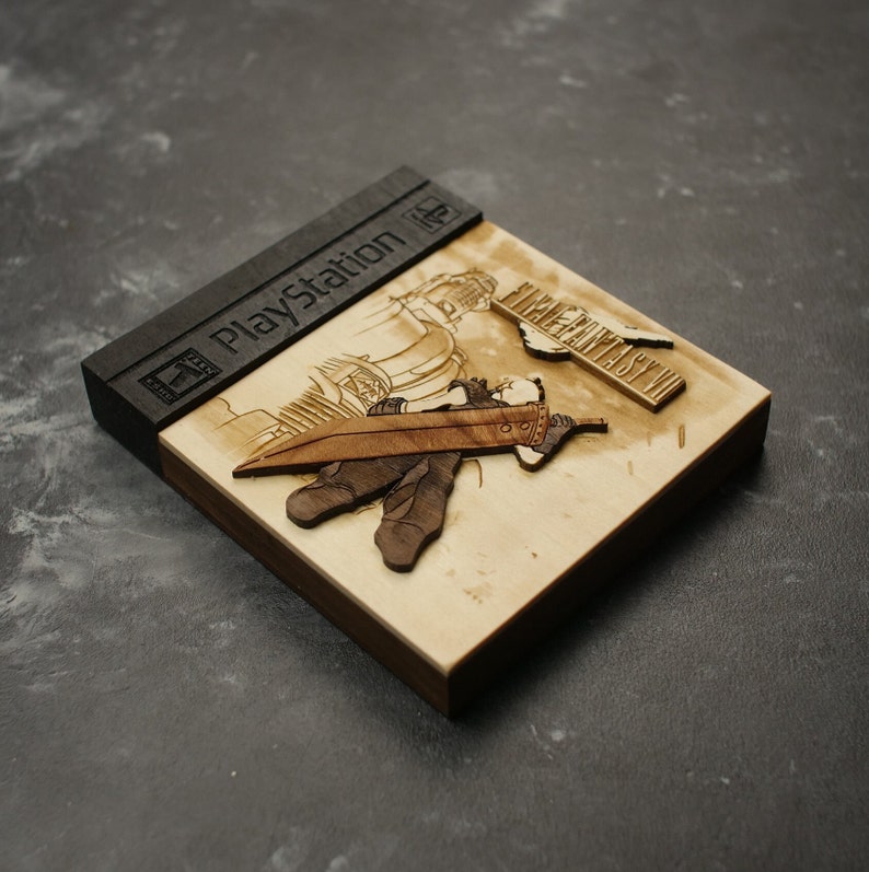 K&ouml;nnte beinhalten: Ein h&ouml;lzerner PlayStation-Spielekoffer mit einem Laser-Cut-Design eines Charakters aus Final Fantasy VII. Der Koffer ist schwarz und hat das PlayStation-Logo auf der Vorderseite. Der Charakter h&auml;lt ein Schwert und steht vor einem Geb&auml;ude.