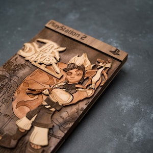 May include: A wooden, laser-cut replica of the Jak and Daxter: The Lost Frontier video game cover art for the Playstation 2. The cover features Jak, a young boy with orange hair, wearing a brown vest and pants, holding a weapon. The background is a brown, textured surface.