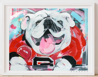 May include: A white bulldog with a pink tongue sticking out, wearing a red and black jersey with a white 'G' on the front. The bulldog is painted in a colorful abstract style.