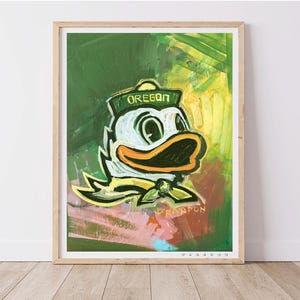 May include: A framed art print featuring a stylized illustration of the Oregon Ducks mascot. The artwork showcases the duck in a sailor hat with the word "OREGON" and a yellow bow tie against a green and yellow background.