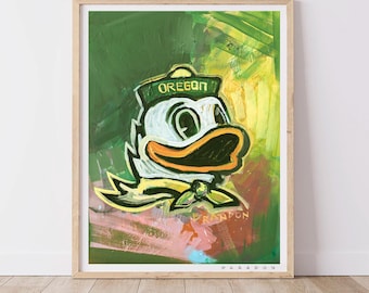 May include: A framed art print featuring a stylized illustration of the Oregon Ducks mascot. The artwork showcases the duck in a sailor hat with the word "OREGON" and a yellow bow tie against a green and yellow background.