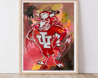 May include: A framed artwork featuring a stylized red bull mascot with white accents and the letters "IU" in white. The bull is set against a colorful abstract background with shades of red, orange, and brown. The artwork is signed.