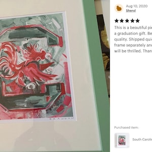 May include: A framed painting of a red rooster with a green and white background. The rooster is the mascot for the University of South Carolina Gamecocks. The painting is signed "Brandon".