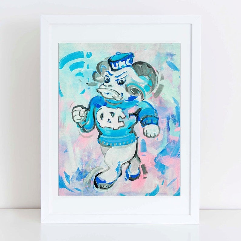 Pu&ograve; includere: Un dipinto blu e bianco di un ariete di cartone animato che indossa un cappello blu con le lettere "UNC" su di esso. L'ariete indossa un maglione blu con le lettere "UNC" su di esso. Lo sfondo &egrave; un mix di blu, rosa e bianco.