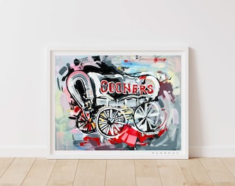May include: A colorful abstract painting of a wagon with the word "SOONERS" written on the side. The wagon is painted in shades of black, white, red, and blue. The background is a mix of abstract shapes and colors.