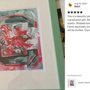 K&ouml;nnte beinhalten: Ein gerahmtes Gem&auml;lde eines roten Hahns vor gr&uuml;nem und wei&szlig;em Hintergrund. Der Hahn ist das Maskottchen der University of South Carolina Gamecocks. Das Gem&auml;lde ist mit "BRANDON" signiert.