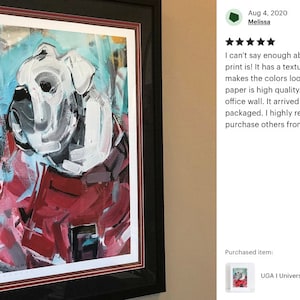 K&ouml;nnte beinhalten: Ein gerahmter Druck eines wei&szlig;en Bulldogs mit roten, blauen und schwarzen abstrakten Farbflecken. Der Druck tr&auml;gt den Titel "UGA I University of Georgia Throwback..."