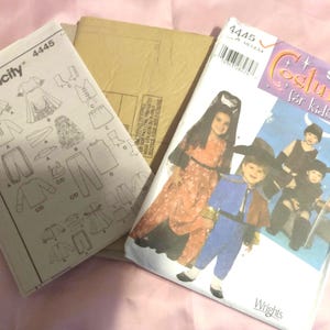May include: Simplicity sewing pattern number 4445 for costumes for kids. The pattern includes instructions for making a witch, a pirate, and two other costumes. The pattern is printed on white paper with black ink.