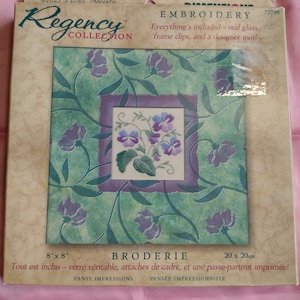 May include: A Regency Collection embroidery kit featuring a pansy design. The kit includes real glass, frame clips, and a designer mat. The kit measures 8 inches by 8 inches.