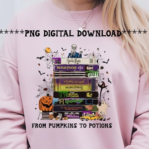 May include: Pink sweatshirt featuring a stack of Halloween-themed VHS tapes with titles like "Hocus Pocus" and "Goosebumps." The design includes bats, cobwebs, a pumpkin, and the text "FROM PUMPKINS TO POTIONS."