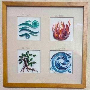 Pode incluir: Uma obra de arte emoldurada com ilustra&ccedil;&otilde;es de quilling de papel representando os quatro elementos: ar, fogo, terra e &aacute;gua. Cada elemento &eacute; exibido em um quadrado, com seu nome acima. A moldura &eacute; feita de madeira marrom clara.