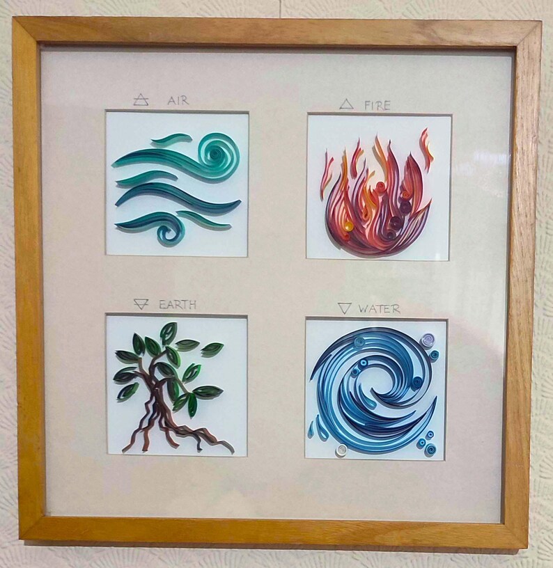 Pode incluir: Uma obra de arte emoldurada com ilustra&ccedil;&otilde;es de quilling de papel representando os quatro elementos: ar, fogo, terra e &aacute;gua. Cada elemento &eacute; exibido em um quadrado, com seu nome acima. A moldura &eacute; feita de madeira marrom clara.