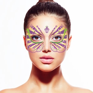 May include: A woman wearing a purple, yellow, and green face mask with a fleur-de-lis design. The mask is a masquerade style with a decorative pattern.