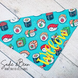 May include: A turquoise blue bandana with a sushi pattern and the word "Welcome" embroidered in yellow.