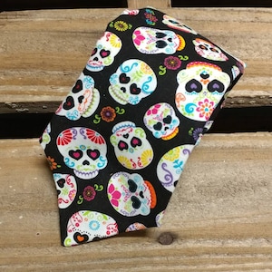 May include: A black tie with a colorful sugar skull pattern. The skulls are white with pink, blue, green, and yellow details. The tie is perfect for a Halloween party or a Day of the Dead celebration.