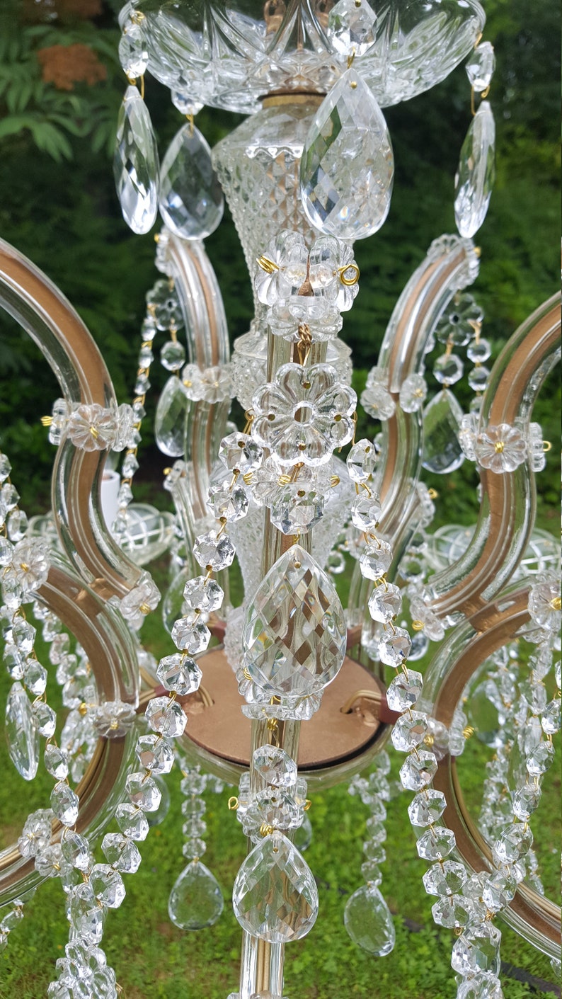 May include: A vintage chandelier with clear crystal teardrop pendants and strands of crystal beads. The chandelier has a gold-toned metal frame and decorative crystal accents, creating a classic and elegant look.