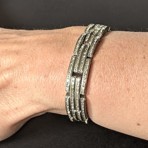 May include: A silver bracelet with a row of clear cubic zirconia stones set in each link.