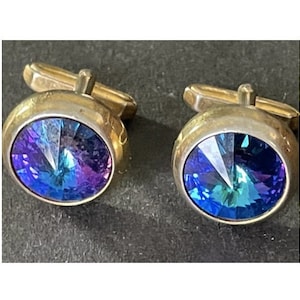 May include: A pair of gold cufflinks with blue and purple iridescent glass stones.