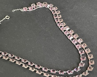 May include: A double-strand necklace with a silver chain and pink square-shaped stones.