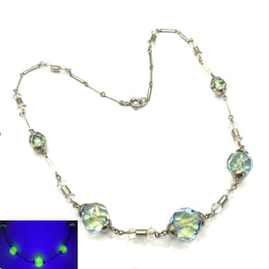 May include: A vintage necklace with iridescent green and blue faceted beads, clear crystal beads, and a silver-tone chain. The necklace's beads glow under a black light. The necklace is a classic piece of jewellery.
