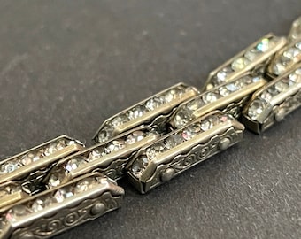May include: A silver bracelet with a chain link design. Each link is set with clear rhinestones.