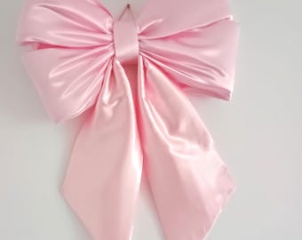 May include: A large, pink satin bow with long tails. The bow is tied in a classic knot and is perfect for adding a touch of elegance to any occasion.
