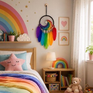 Könnte beinhalten: Ein kreisförmiger Traumfänger mit einem schwarzen Netzrahmen und einer Spirale aus regenbogenfarbenem Garn in der Mitte. An der Unterseite hängen mehrere lange, leuchtende Federn in den Farben Violett, Blau, Grün, Gelb, Orange und Rot.