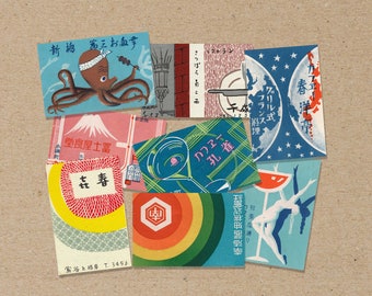 May include: A collection of vintage matchbook covers featuring various designs. The covers are colorful and feature illustrations of a octopus, a mountain, a peacock, a cafe, a restaurant, and a woman in a dress. The text on the covers includes "新梅第三お教章", "小国町", "堂食屋士富", "在春", "レストラン", "カフェ", "さっぽろあこ", "春洋亭", "フランス", "アリル式", "スー", "理", "谷上根岸 T. 3456", "カフェー", "孔雀", "邦楽座通り".