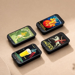 May include: Four small, black rectangular tins with vintage advertising art. The tins feature images of a woman, a horse, and a glass of beer. The text on the tins includes "Absinthe Blanche", "La Chablisienne", "Rhums Incas", and "Lengrand".