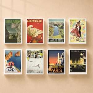 May include: A collection of eight vintage-style travel posters featuring illustrations of Ireland, Greece, Lake of Thun, Spain, Capri, Copenhagen, Paris, and Deutschland. Each rectangular print displays iconic landmarks, landscapes, and cultural scenes.