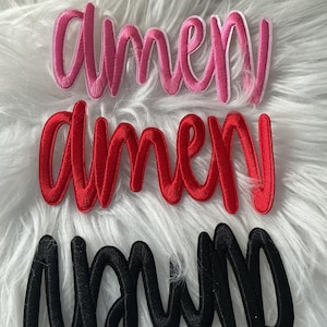 May include: Three embroidered patches featuring the word amen in a cursive script font. The top patch is pink with a white border, the middle patch is solid red, and the bottom patch is solid black. Each patch has a raised, textured surface.