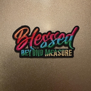 May include: An embroidered patch with a black background featuring the word Blessed in a multi-colored gradient script font, with the words BEYOND MEASURE embroidered in a block font below in green and yellow thread.
