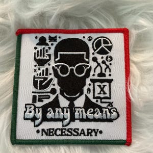 Pode incluir: Patch quadrado com fundo branco, uma silhueta preta de uma pessoa com óculos e vários símbolos. O texto "By any means" e "Necessary" está em branco. O patch tem uma borda vermelha e verde.